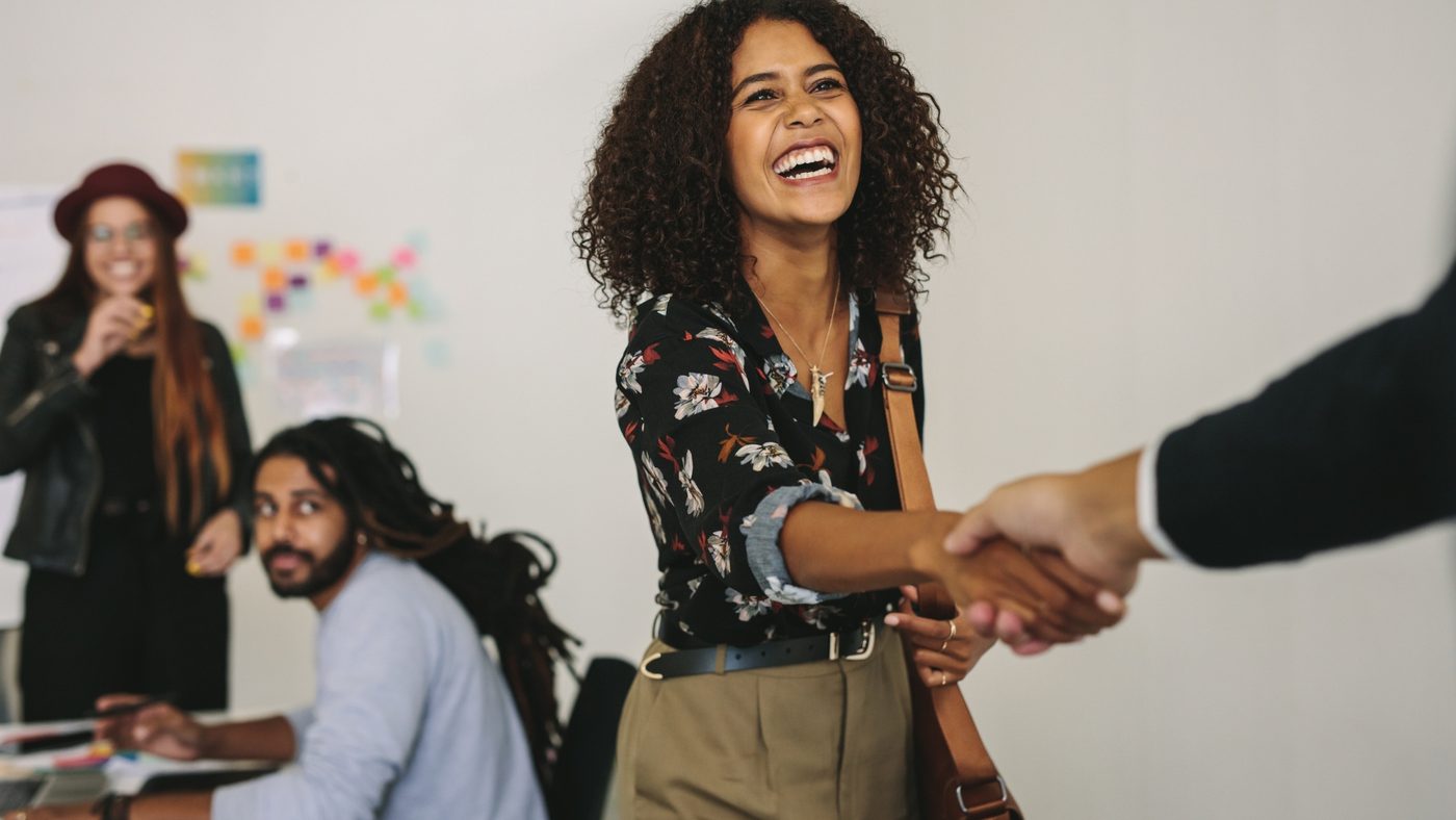 Woman smiling and shaking hands with a colleague in an office
