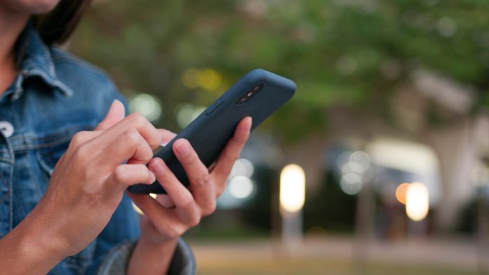 Close-up of hands using a smartphone outdoors in the evening