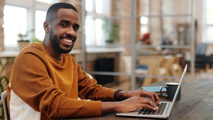 Smiling man working on a laptop at a table